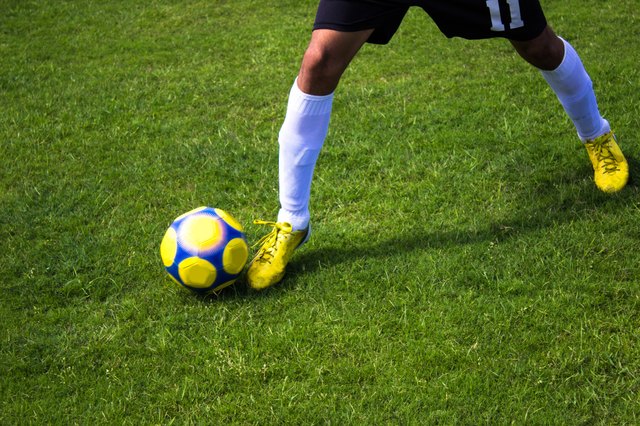 Low section of soccer player carrying ball in soccer field