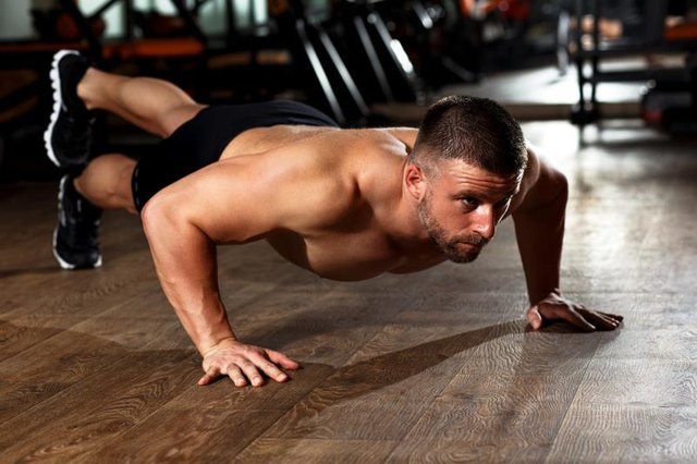 Muscular man doing a pushups at gym.