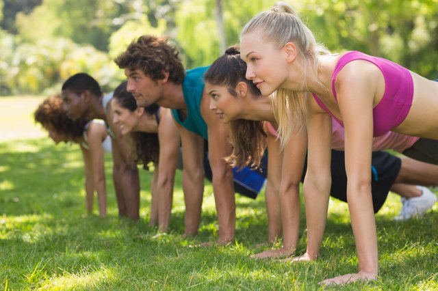 Group of fitness people doing push ups in park
