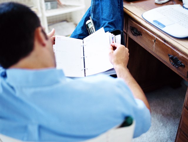 shot of a man sitting on a chair and looking through a diary