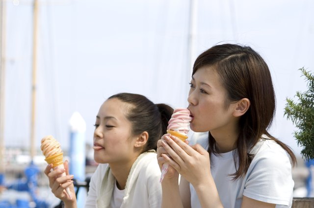 Two young Japanese women eating soft ice cream at port