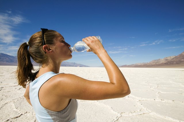 Woman in desert with water bottle, Bonneville Salt Flats, Utah, USA
