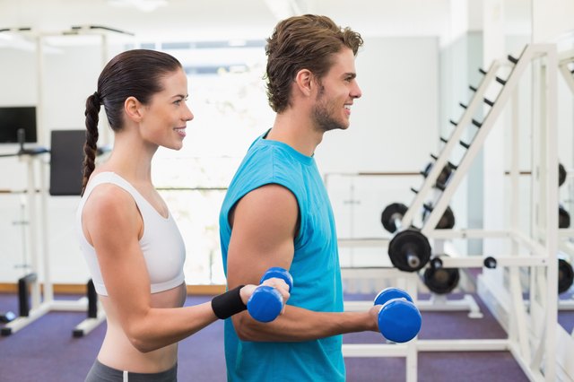 Fit couple exercising with blue dumbbells