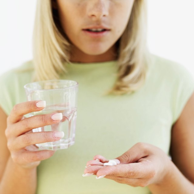 close-up of a young woman holding a glass of water and pills