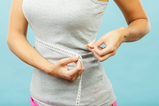 Fitness girl measuring her waistline