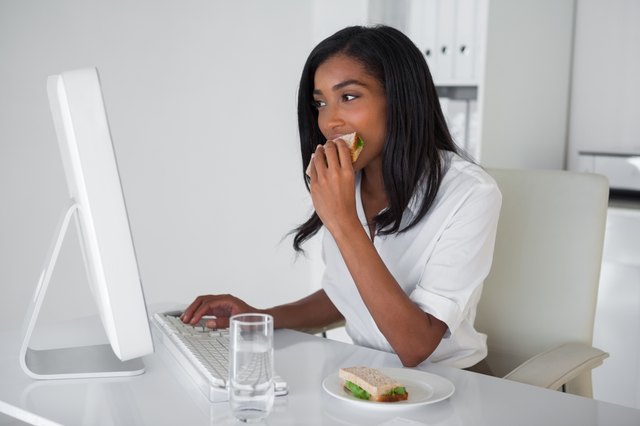 Pretty businesswoman eating a sandwich at her desk