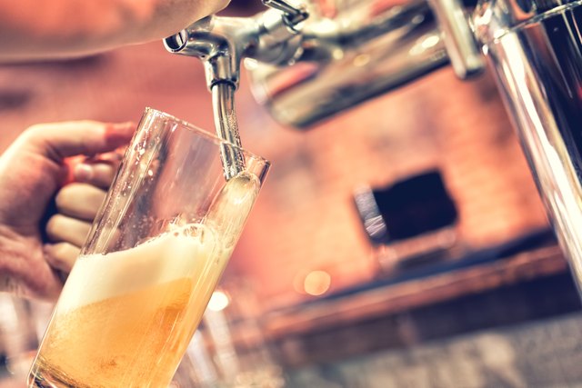 Hand of bartender pouring a large lager beer in tap
