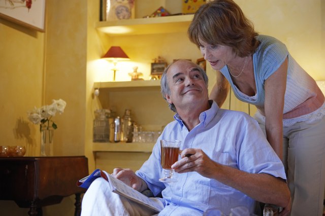 Mature couple relaxing in living room, woman at man's shoulder