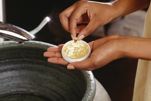 Woman holding vitamin E capsules, close-up of hands