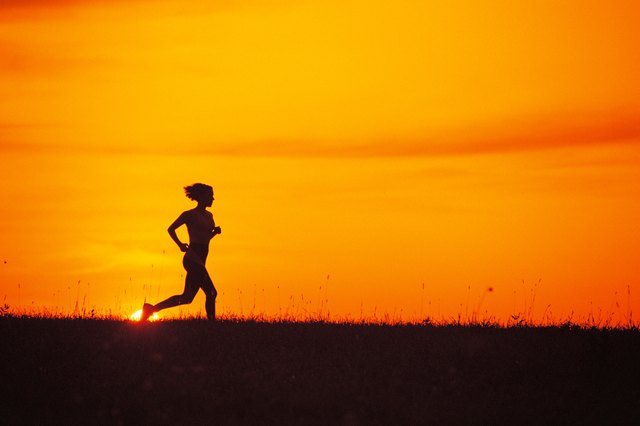 Silhouette of woman jogging at sunrise or sunset