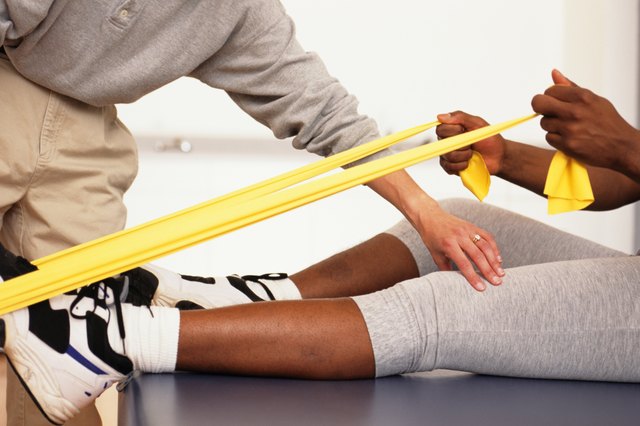 Man bending forward in physical therapy centre, woman supervising, surface view