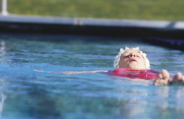 Woman floating on back in outdoor pool, surface view