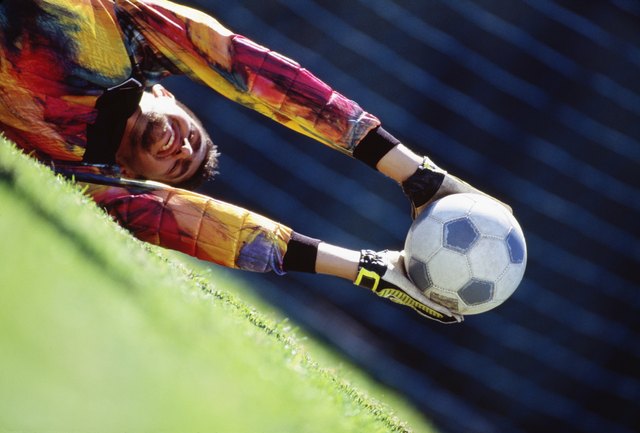Soccer goalie lunging and catching ball