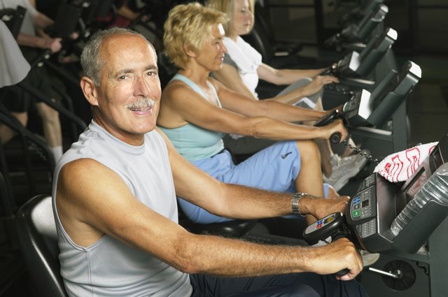 Mature man on cycling machine in gym, smiling, portrait
