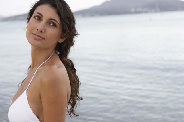 Young woman standing on beach, looking over shoulder