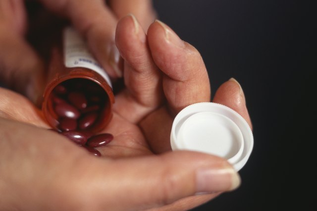 Woman tipping medical pills out of bottle, close up of hands