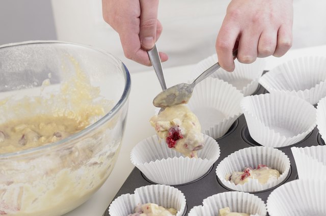 Spooning muffin mixture in to muffin liners on a baking tray