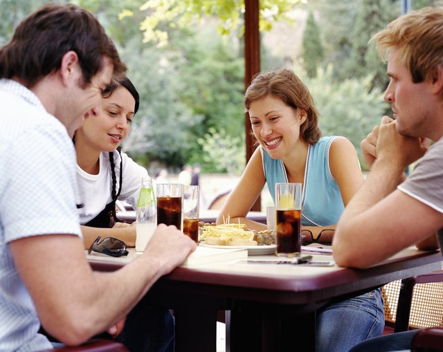 Two couples having drinks at outdoor cafe, smiling