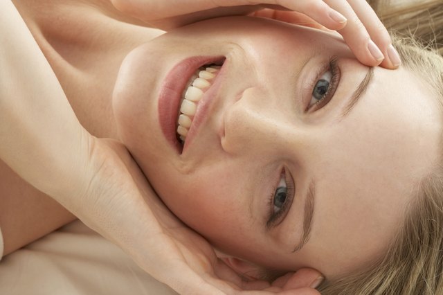 Young woman lying on bed, smiling, portrait, elevated view, close-up