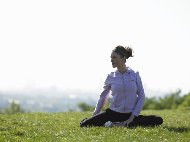 Young woman sitting on grass doing yoga