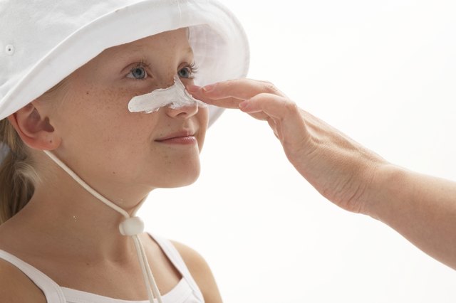Girl (7-9) having sun cream applied to nose