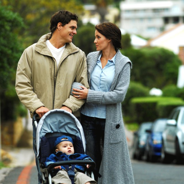mother and father out walking with baby son (12-18 months) in buggy