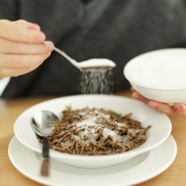 close-up of a man's hand sprinkling sugar on a bowl of cereal