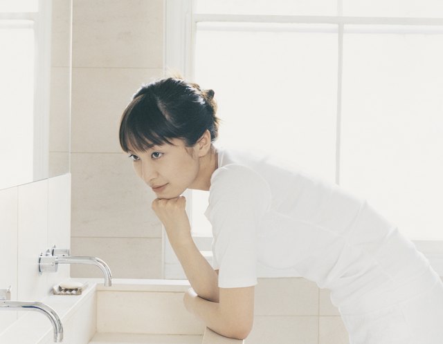 Woman Leans her Elbow on a Bathroom Sink