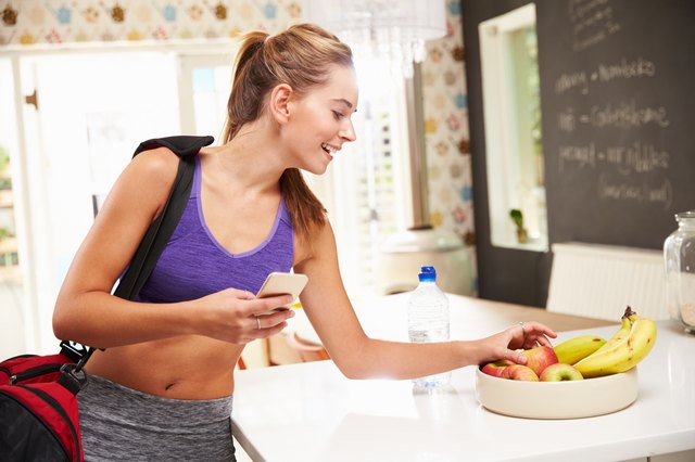 Woman Wearing Gym Clothing Choosing Fruit From Bowl