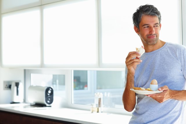 Mature holding his breakfast plate, thoughtful