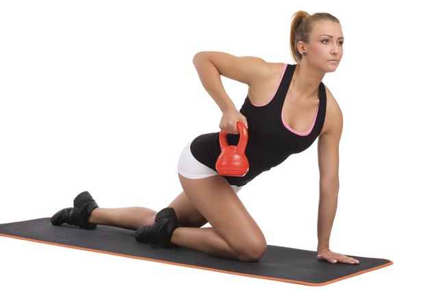 Female Fitness Instructor On Exercise Mat With Kettlebell