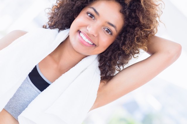 Sporty woman stretching hand behind back in fitness studio