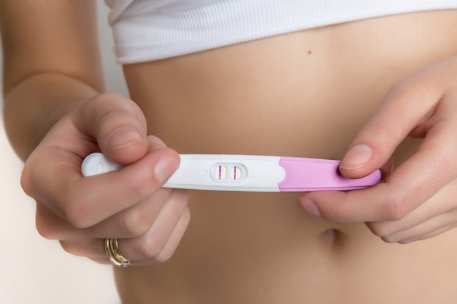 Woman holding positive pregnancy test