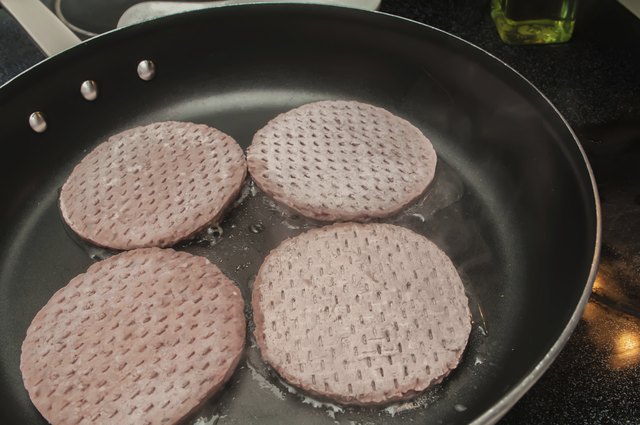 four hamburgers on frying pan