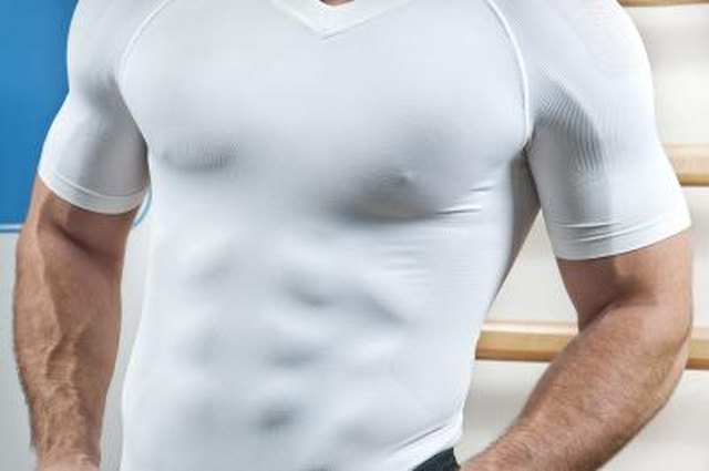 Muscular torso through white shirt in gym.