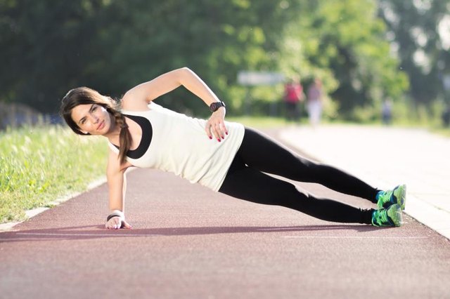 Girl plank sideways, outdoors track.