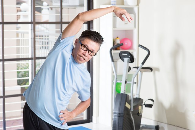 Mature Asian man arms stretching at gym