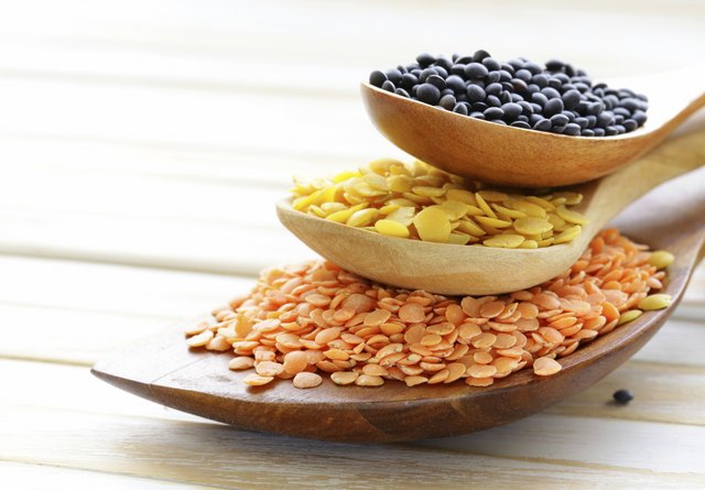 different kinds of lentils in wooden spoons
