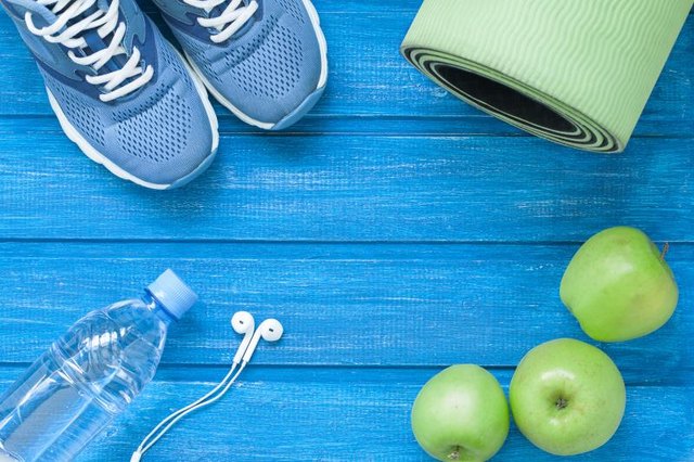 Flat lay sport shoes, bottle of water, mat and earphones on blue wooden background. Concept healthy lifestyle, sport and diet. Selective focus.