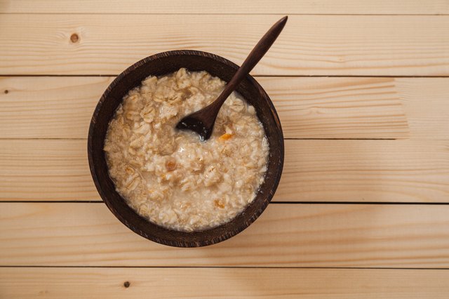 Bowl of hot oatmeal with wooden spoon on the table