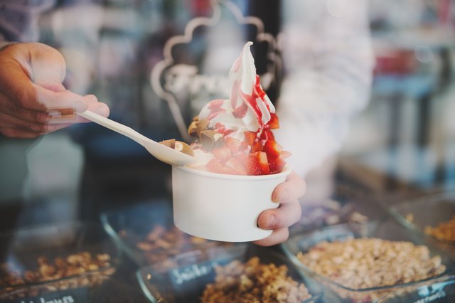 seller pours sauce on a soft frozen yogurt