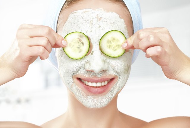 Funny young girl with mask for skin face and cucumbers