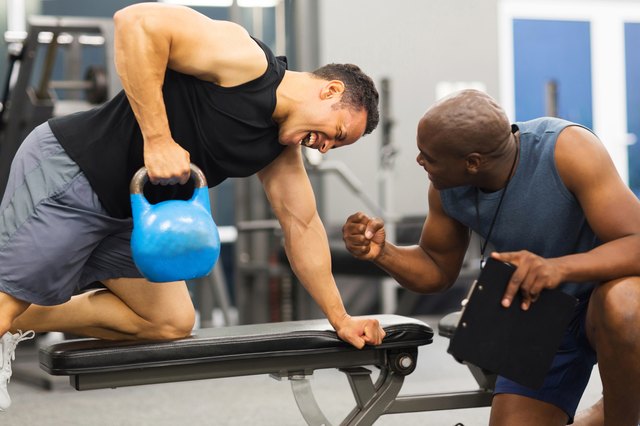 personal trainer training man with kettle bell