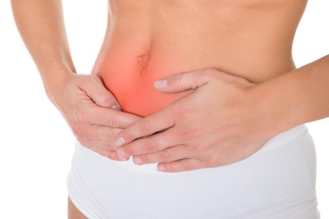 Midsection of young woman suffering from stomach pain over white background