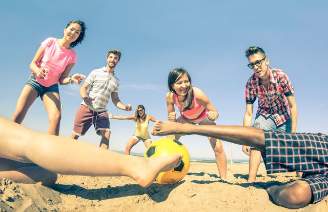 Group of multiracial friends playing beach soccer