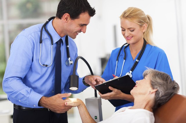 dermatologist and assistant recording senior patient's skin condition