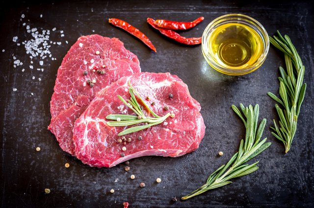 Fresh beef steaks with ingredients on the dark background