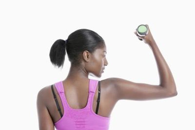 Back view of young woman raising dumbbell over white background