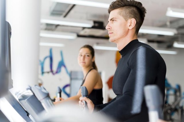 Young healthy group of people working out on a elliptic trainer in a fitness center