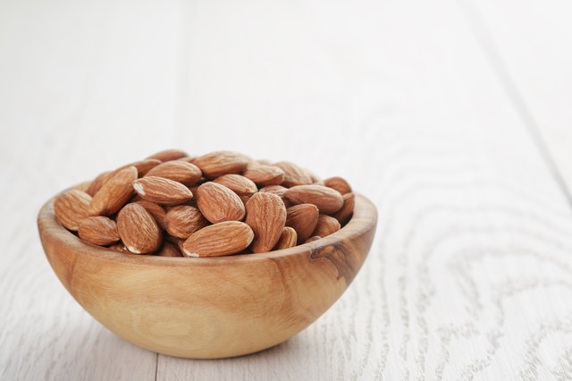 roasted almonds in bowl on white wooden table